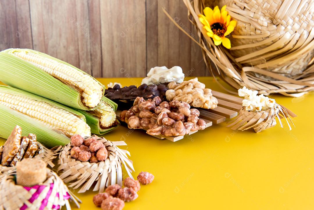 Festa Junina brasileira decorada mesa amarela, chapéu de palha, milho e doces