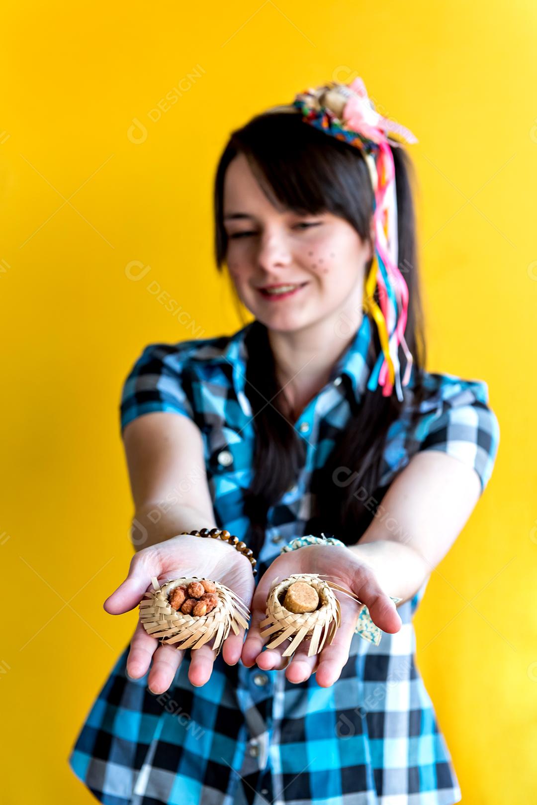 Garota brasileira em festa junina segurando paçoca e doce de amendoim, foco seletivo