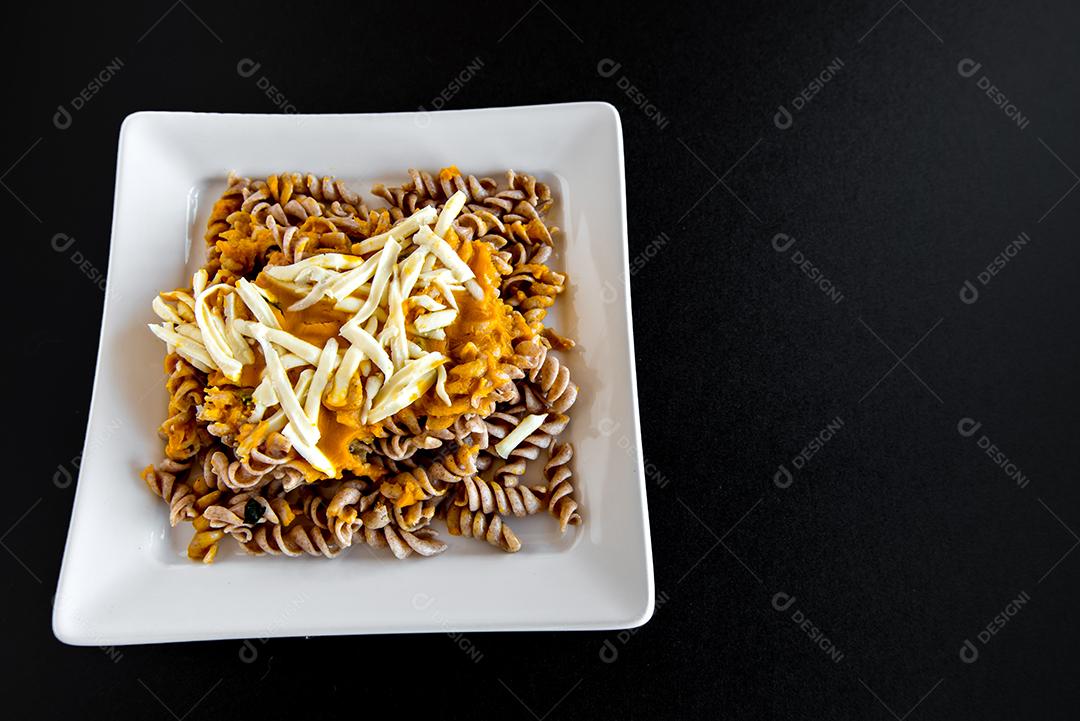 Deliciosa massa Fusilli com molho de abóbora e queijo colonial em fundo preto