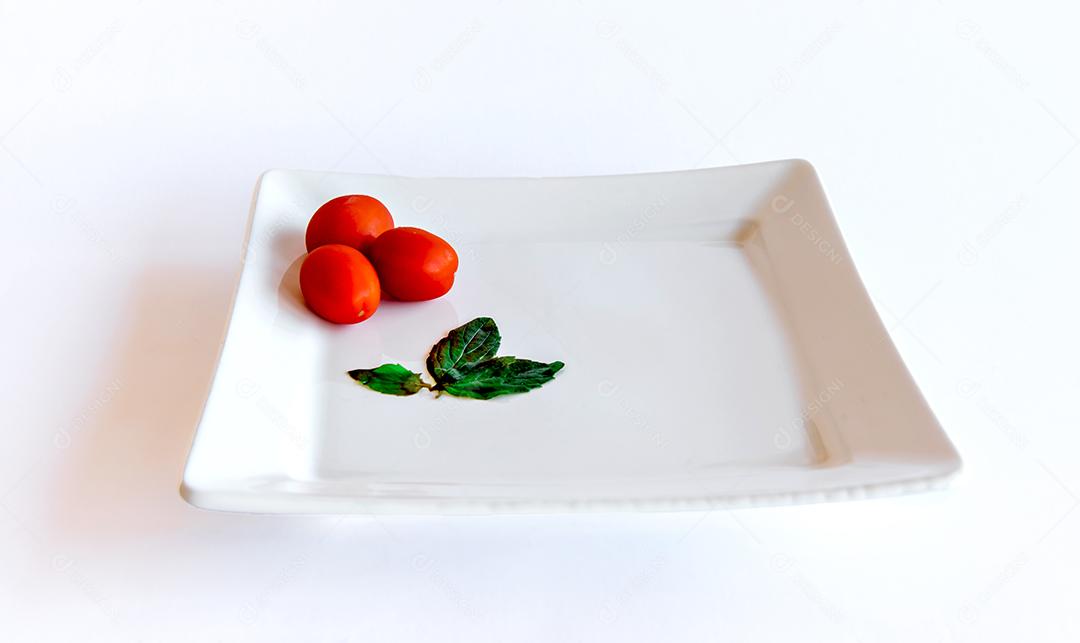 Tomate e manjericão servido em um prato branco sobre fundo branco