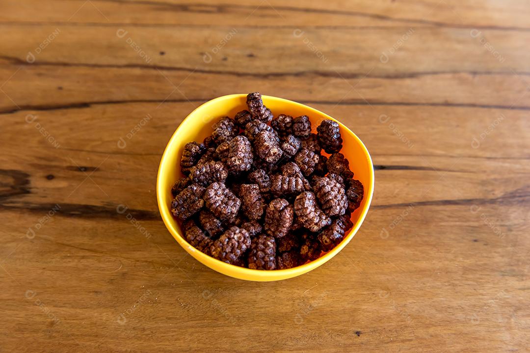 Flocos de milho chocolate na mesa de madeira, café da manhã com leite e flocos de milho