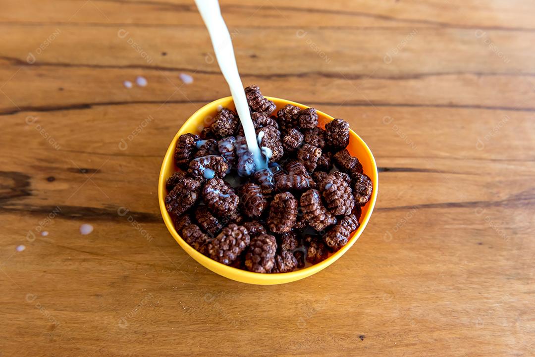 Derramando leite em bolas de chocolate com flocos de milho Café da manhã com leite e flocos de milho