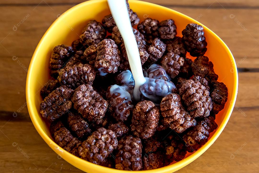 Derramando leite em bolas de chocolate com flocos de milho Café da manhã com leite e flocos de milho