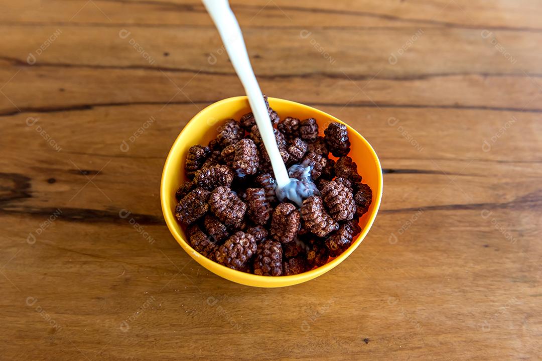 Derramando leite em bolas de chocolate com flocos de milho Café da manhã com leite e flocos de milho