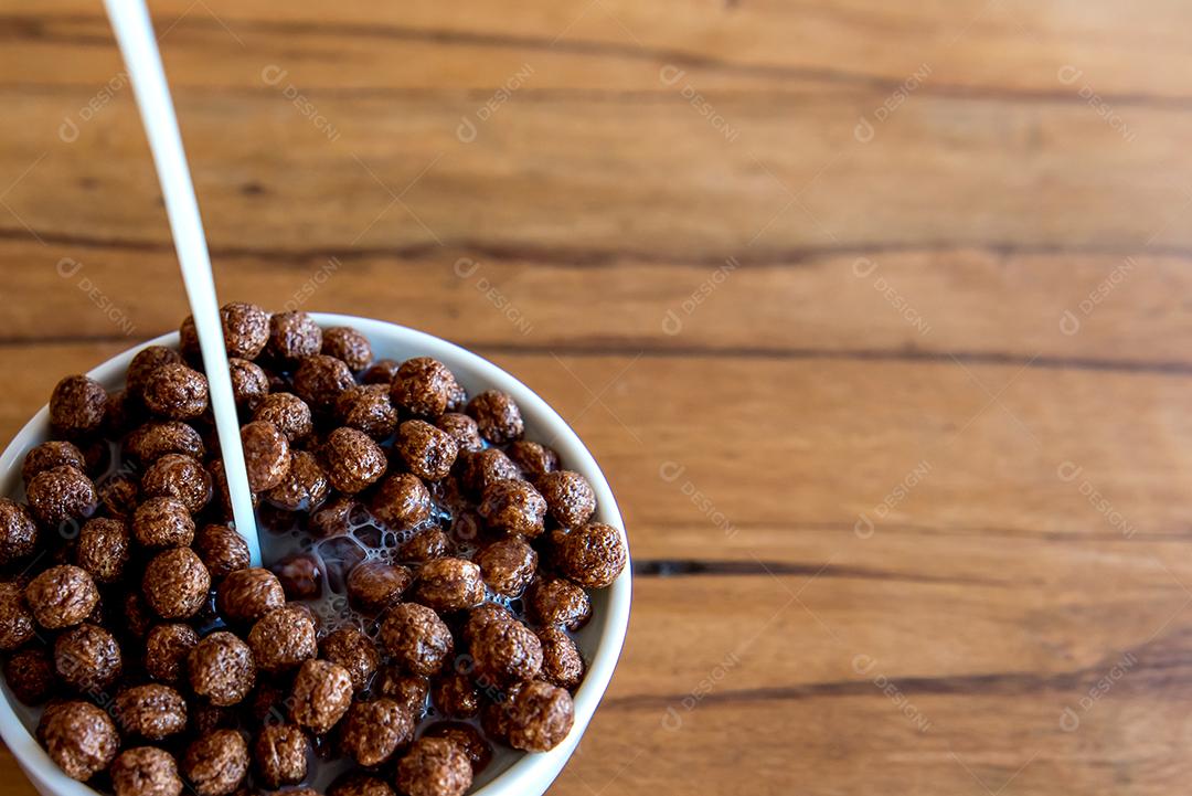 Derramando leite em bolas de chocolate com flocos de milho Café da manhã com leite e flocos de milho