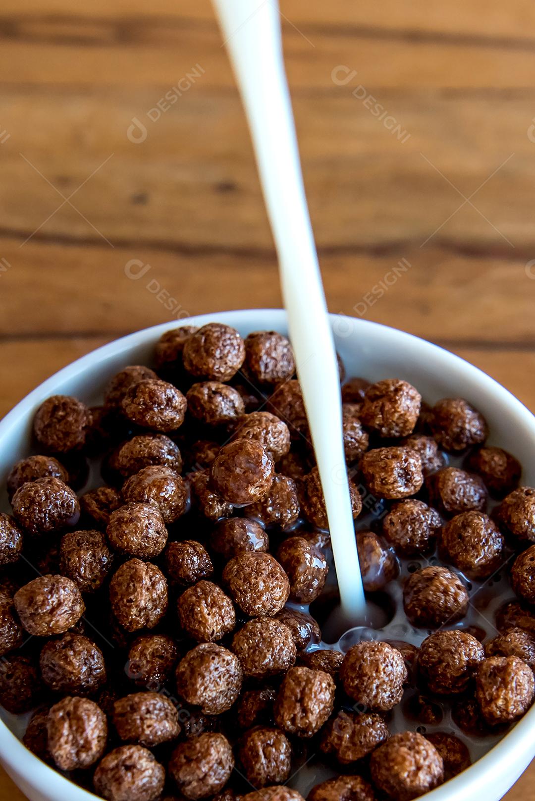 Derramando leite em bolas de chocolate com flocos de milho Café da manhã com leite e flocos de milho