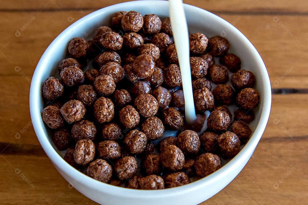 Derramando leite em bolas de chocolate com flocos de milho Café da manhã com leite e flocos de milho