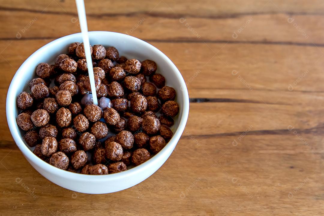 Derramando leite em bolas de chocolate com flocos de milho Café da manhã com leite e flocos de milho