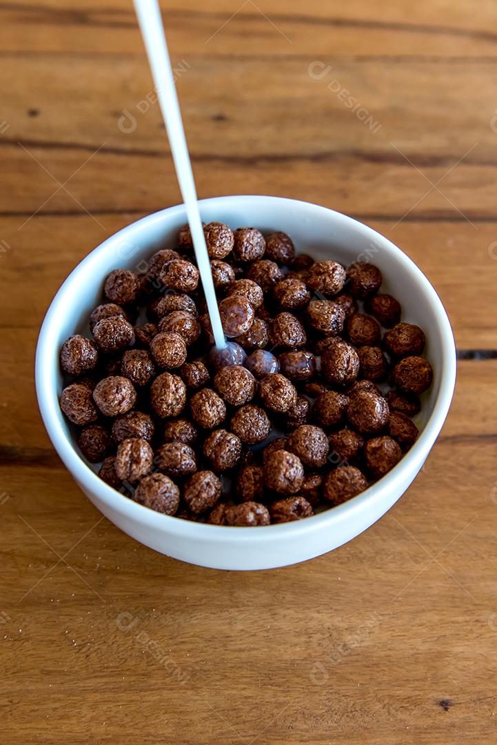 Derramando leite em bolas de chocolate com flocos de milho Café da manhã com leite e flocos de milho