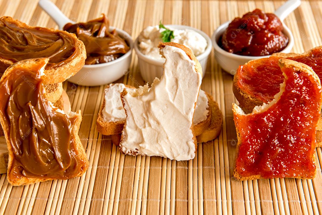 Pão torrado com geléia, doce de leite e creme de ricota em uma mesa de café da manhã