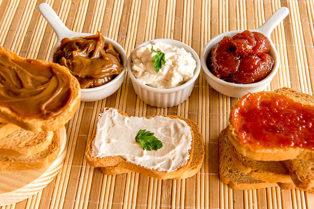Pão torrado com geléia, doce de leite e creme de ricota em uma mesa de café da manhã