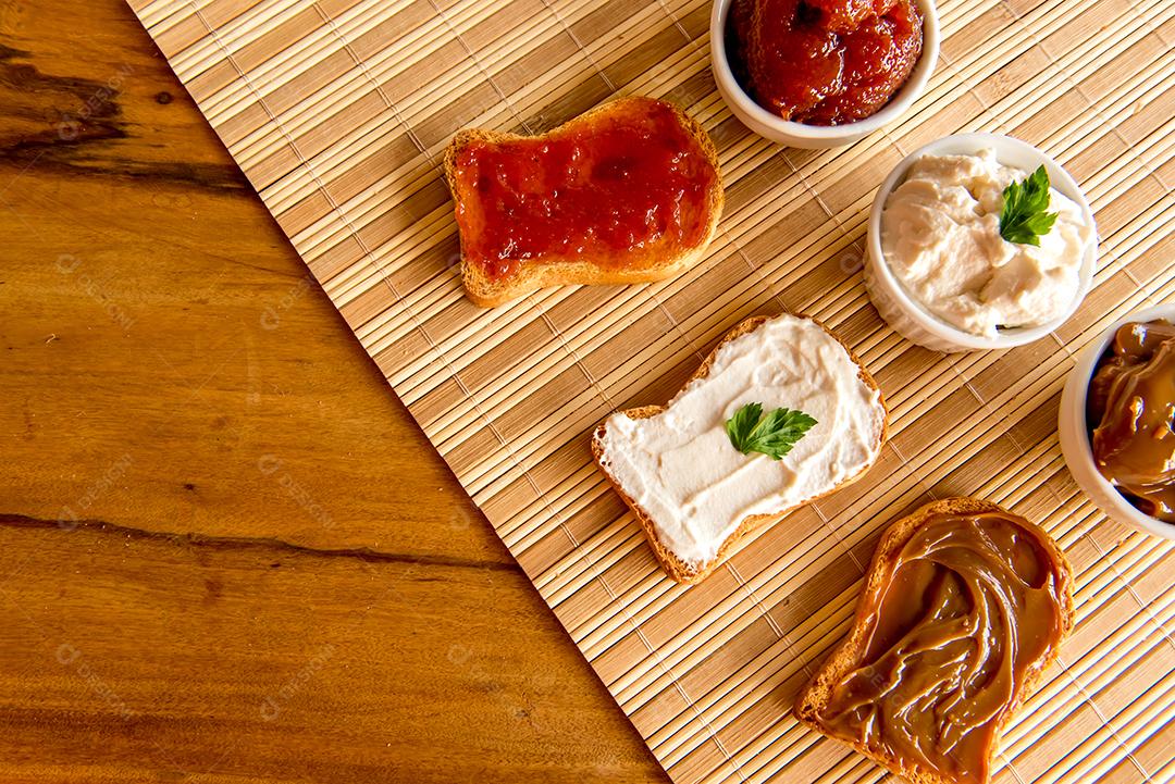 Pão torrado com geléia, doce de leite e creme de ricota em uma mesa de café da manhã