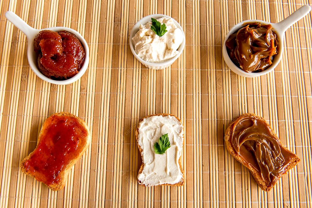 Pão torrado com geléia, doce de leite e creme de ricota em uma mesa de café da manhã