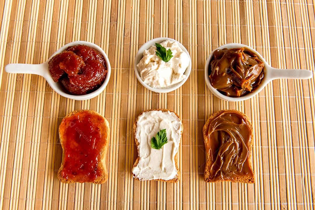 Pão torrado com geléia, doce de leite e creme de ricota em uma mesa de café da manhã