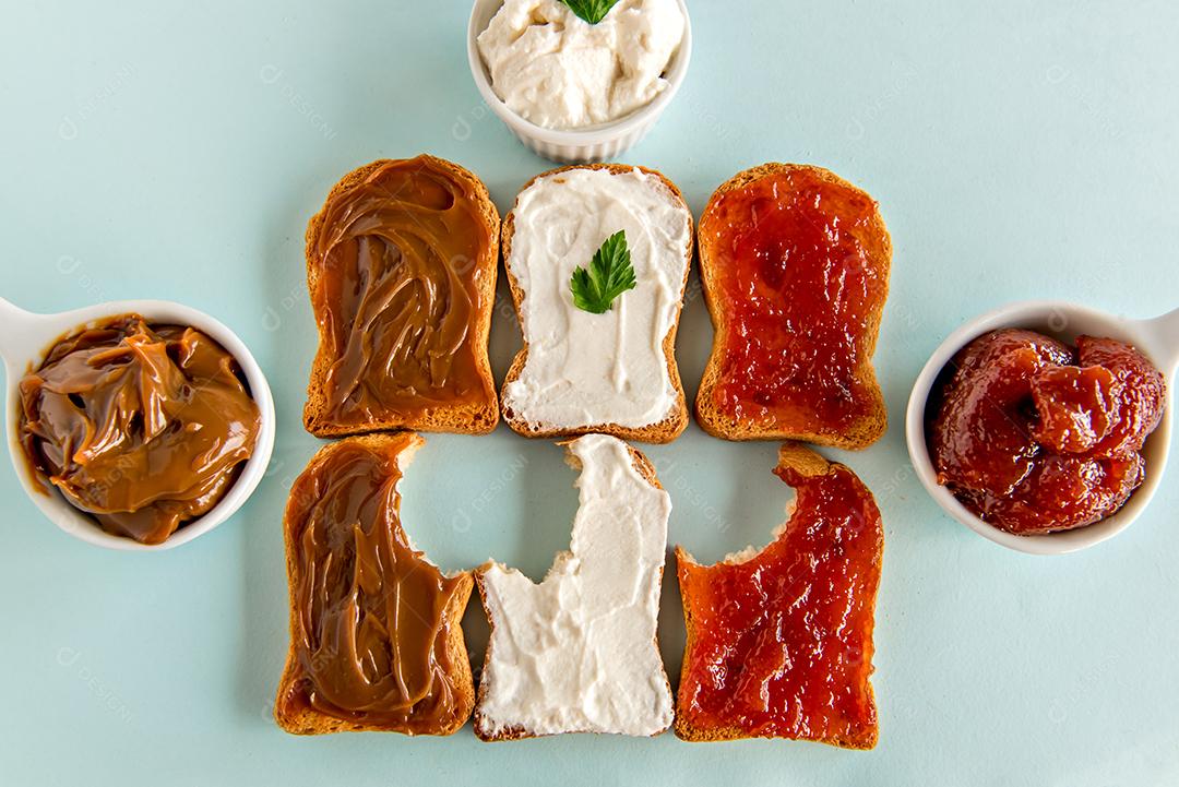 Pão torrado com geléia, doce de leite e creme de ricota em uma mesa de café da manhã