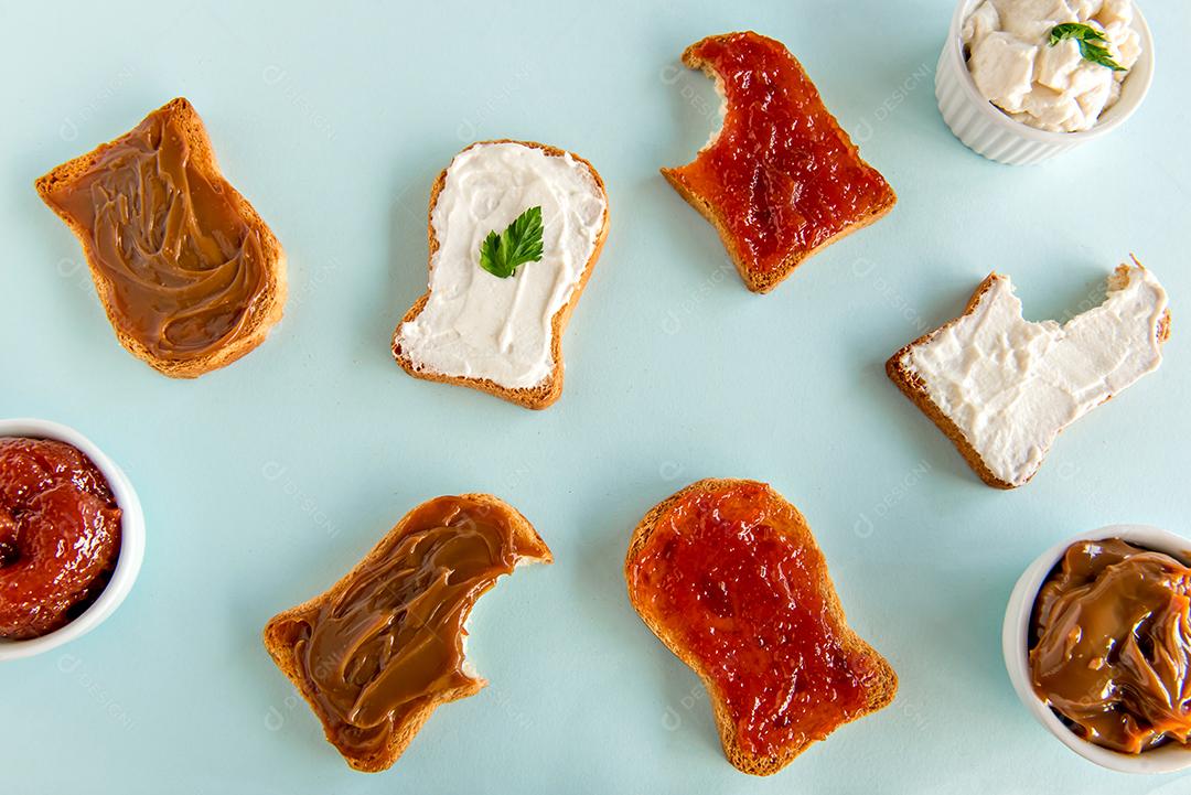Pão torrado com geléia, doce de leite e creme de ricota em fundo azul