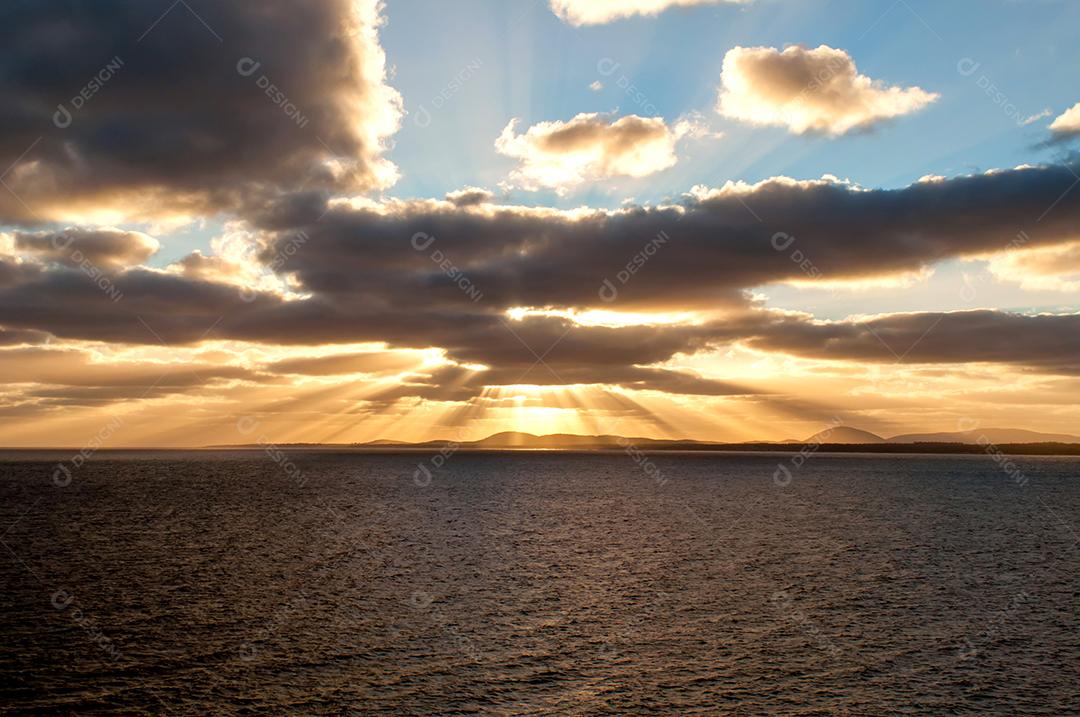 Raios de sol saindo das nuvens ao pôr do sol sobre o mar