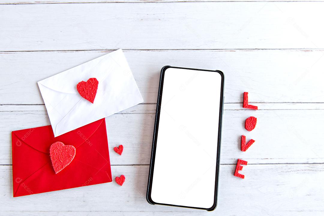 Conceito de dia dos namorados, carta de amor e celular com tela branca na mesa de madeira
