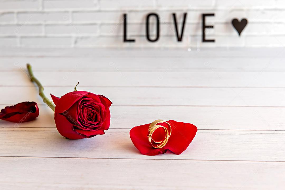 Conceito de dia dos namorados, rosas e anéis de casamento na mesa de madeira