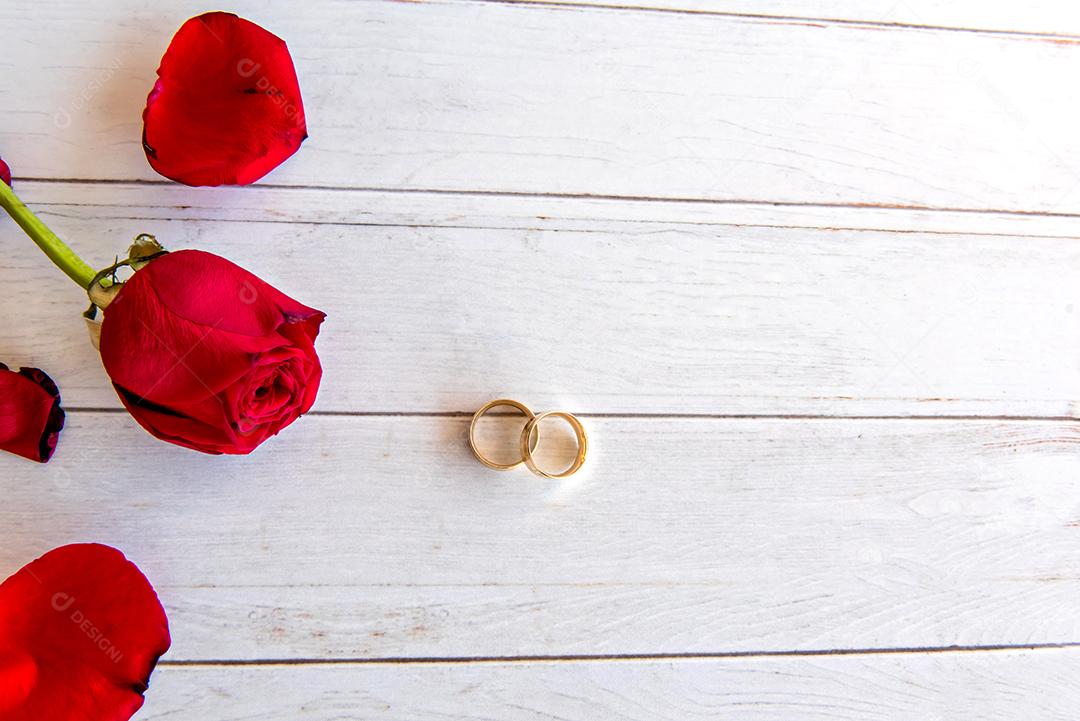 Conceito de dia dos namorados, rosas e anéis de casamento na mesa de madeira