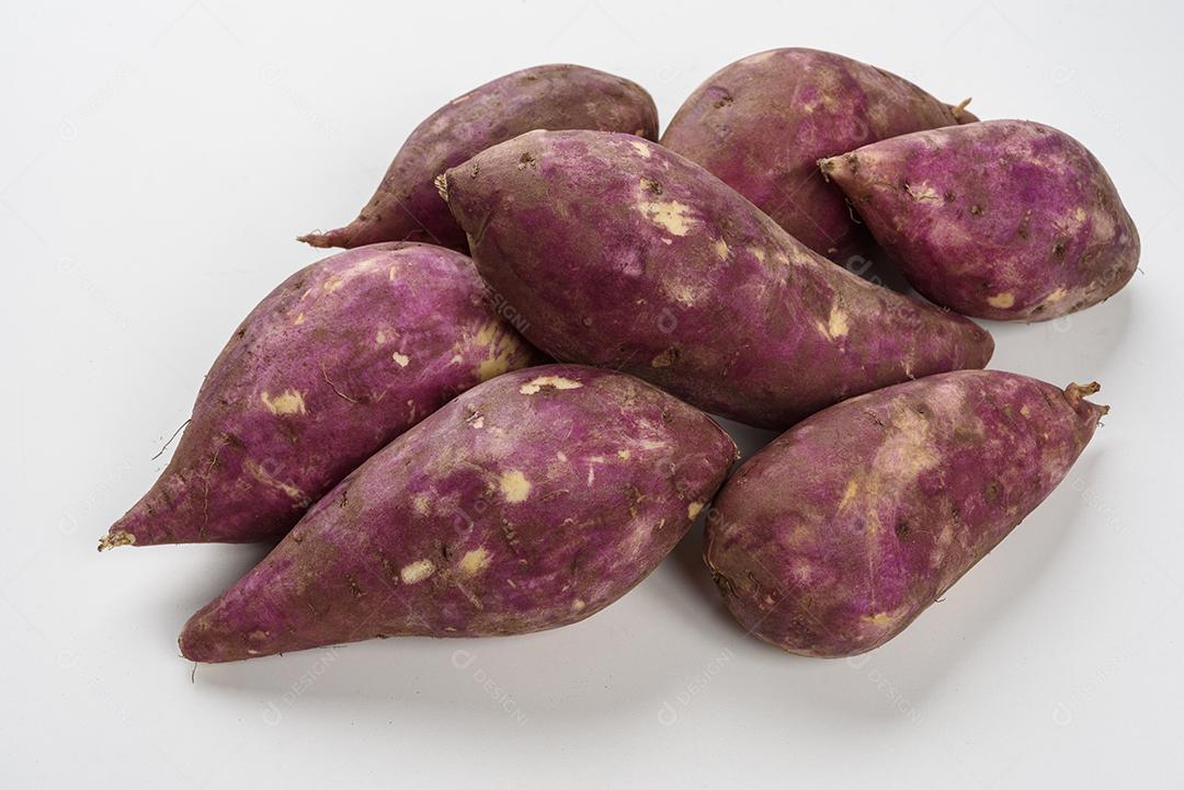 Cesta de palha com batatas doces cruas dentro em fundo branco