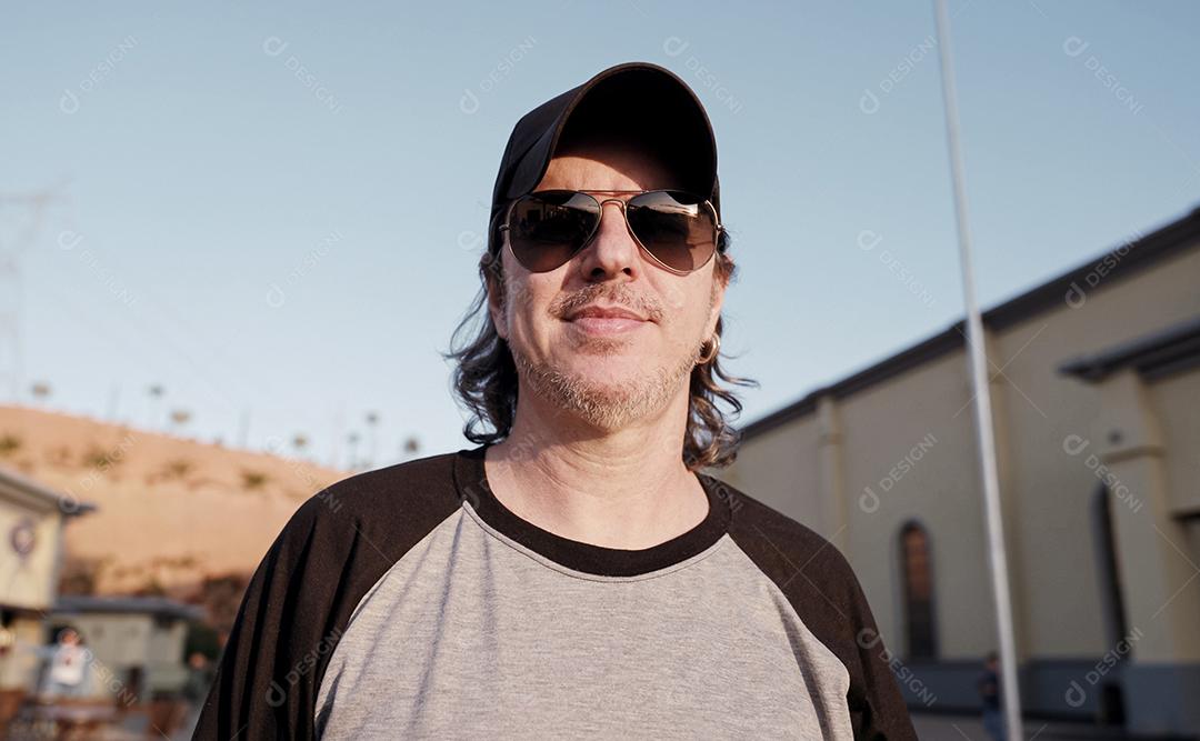 Elegante modelo latino com longos cabelos ruivos e estilo de vida de barba na cidade ao pôr do sol.