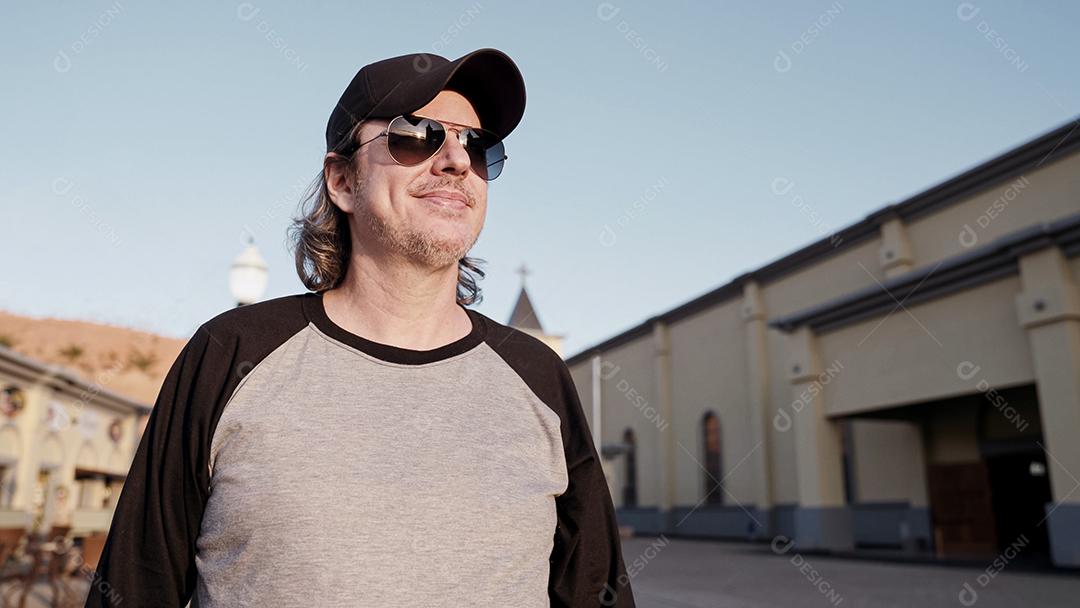 Elegante modelo latino com longos cabelos ruivos e estilo de vida de barba na cidade ao pôr do sol.