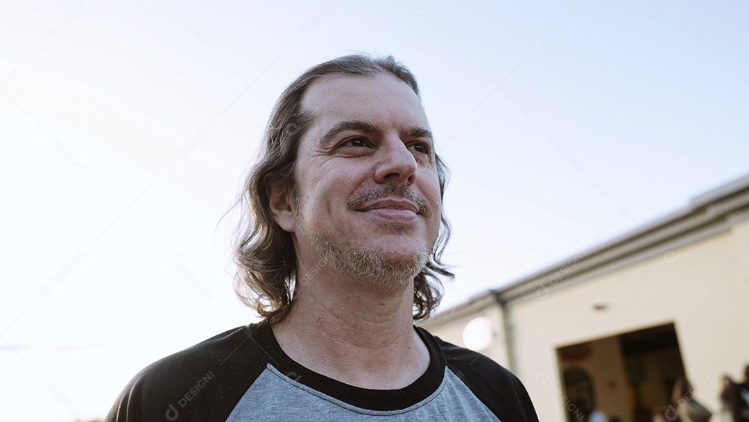 Elegante modelo latino com longos cabelos ruivos e estilo de vida de barba na cidade ao pôr do sol.