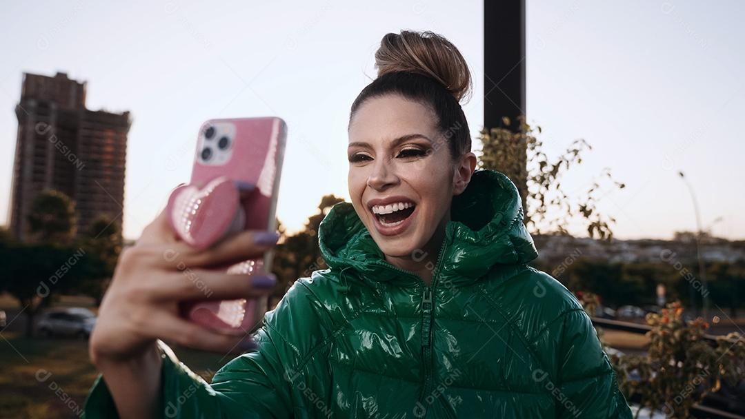 Imagem de uma jovem loira latina animada feliz usando o celular no fundo da cidade