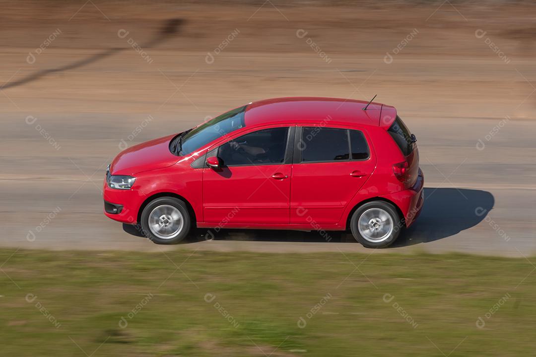 Carro vermelho garimpando na estrada.