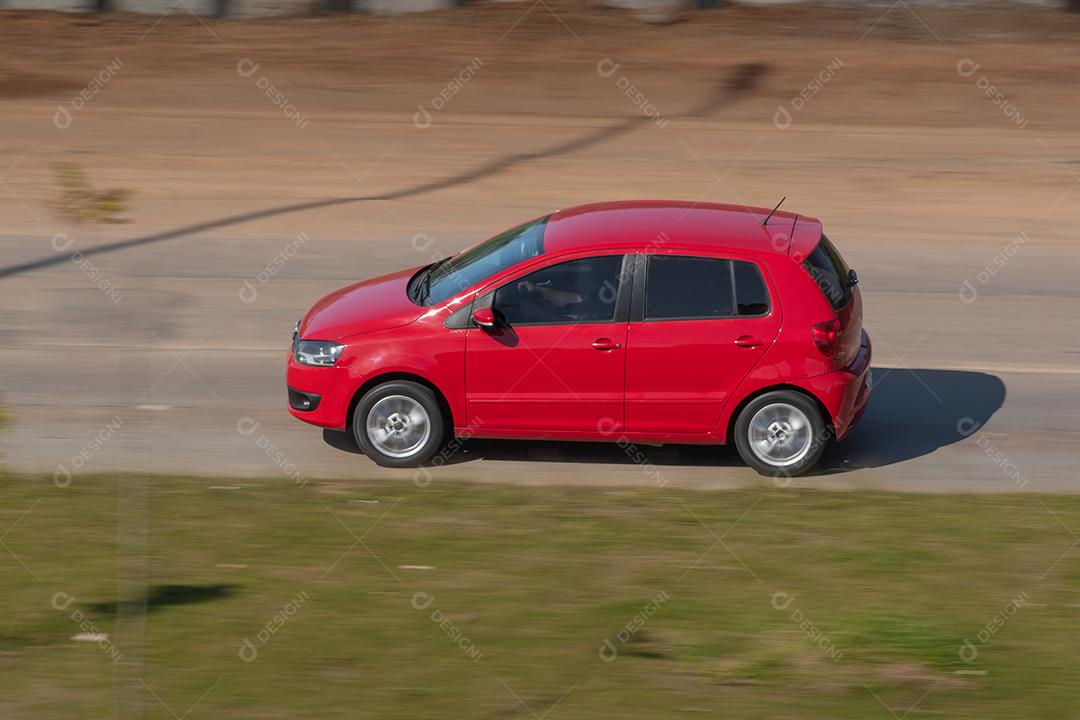 Carro vermelho garimpando na estrada.