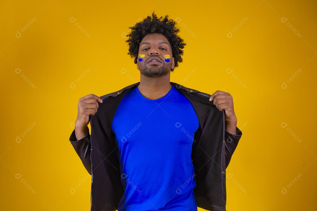 homem negro sobre fundo amarelo com o rosto pintado com azul a