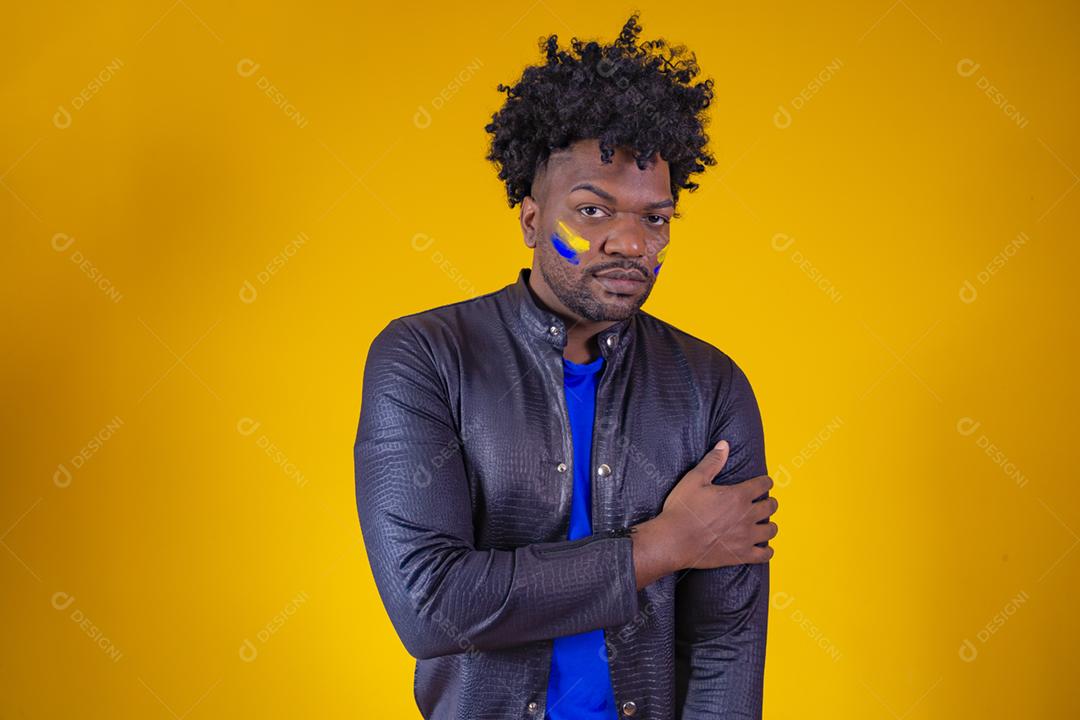 homem negro sobre fundo amarelo com o rosto pintado com azul a