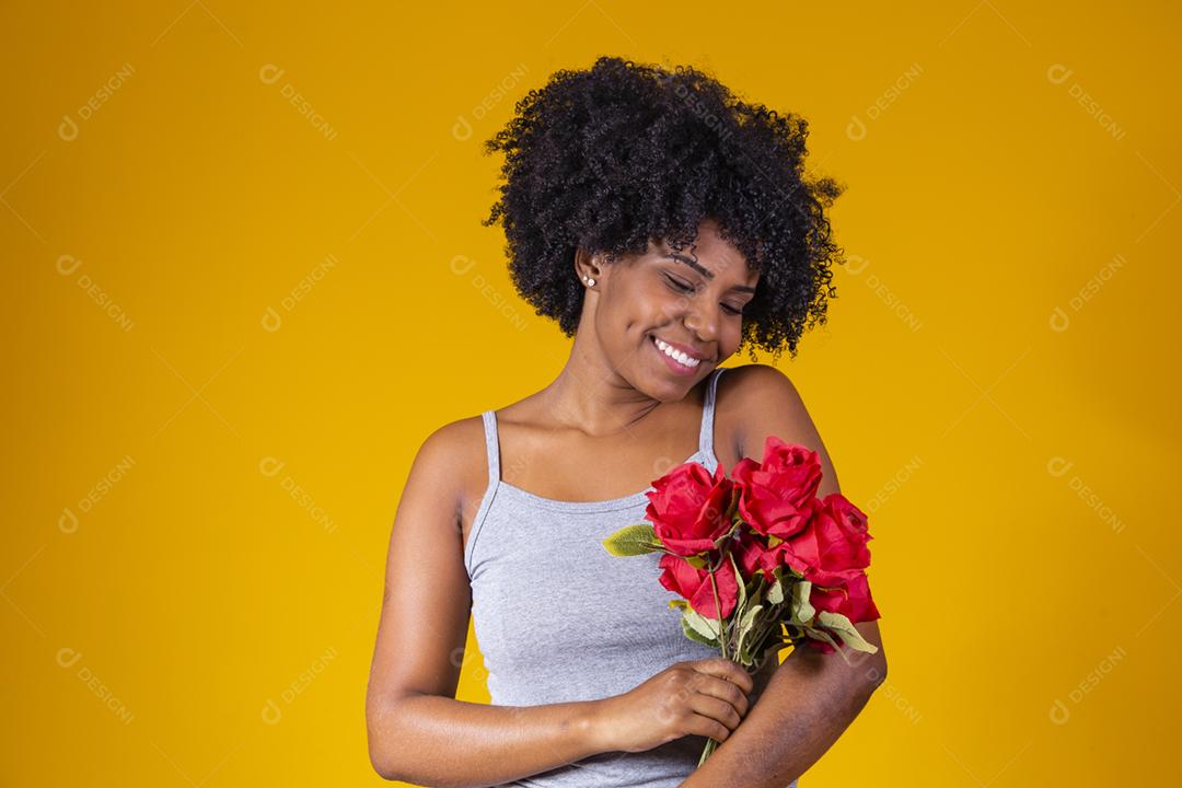 mulher afro sorrindo com buque de flores vermelhas