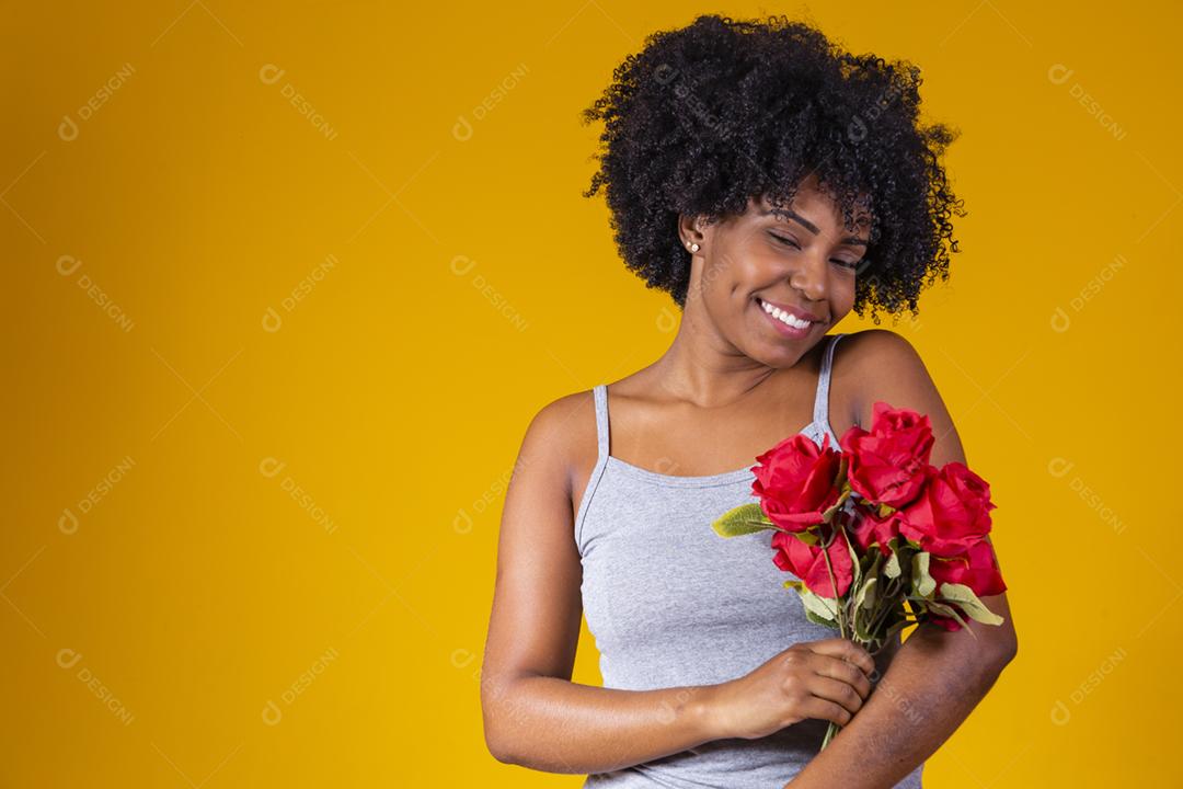 mulher afro sorrindo com buque de flores vermelhas