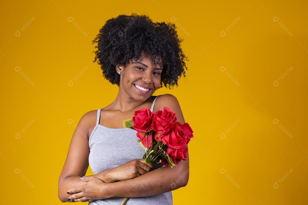 mulher afro sorrindo com buque de flores vermelhas