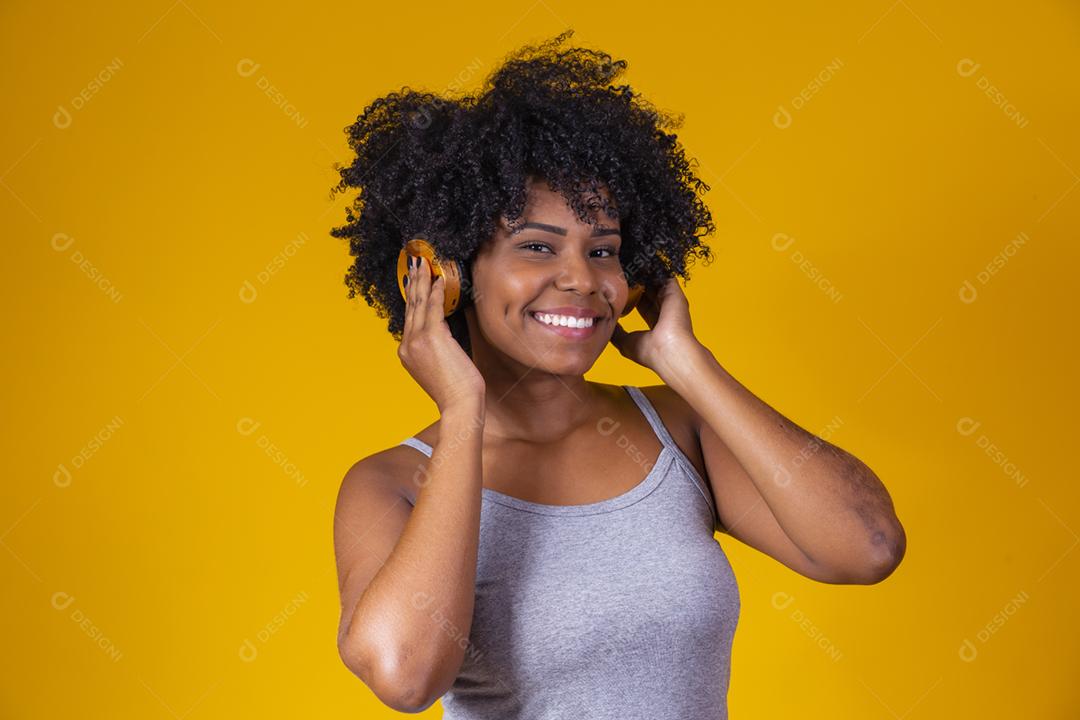 Mulher afro escutando musica com fones de ouvido