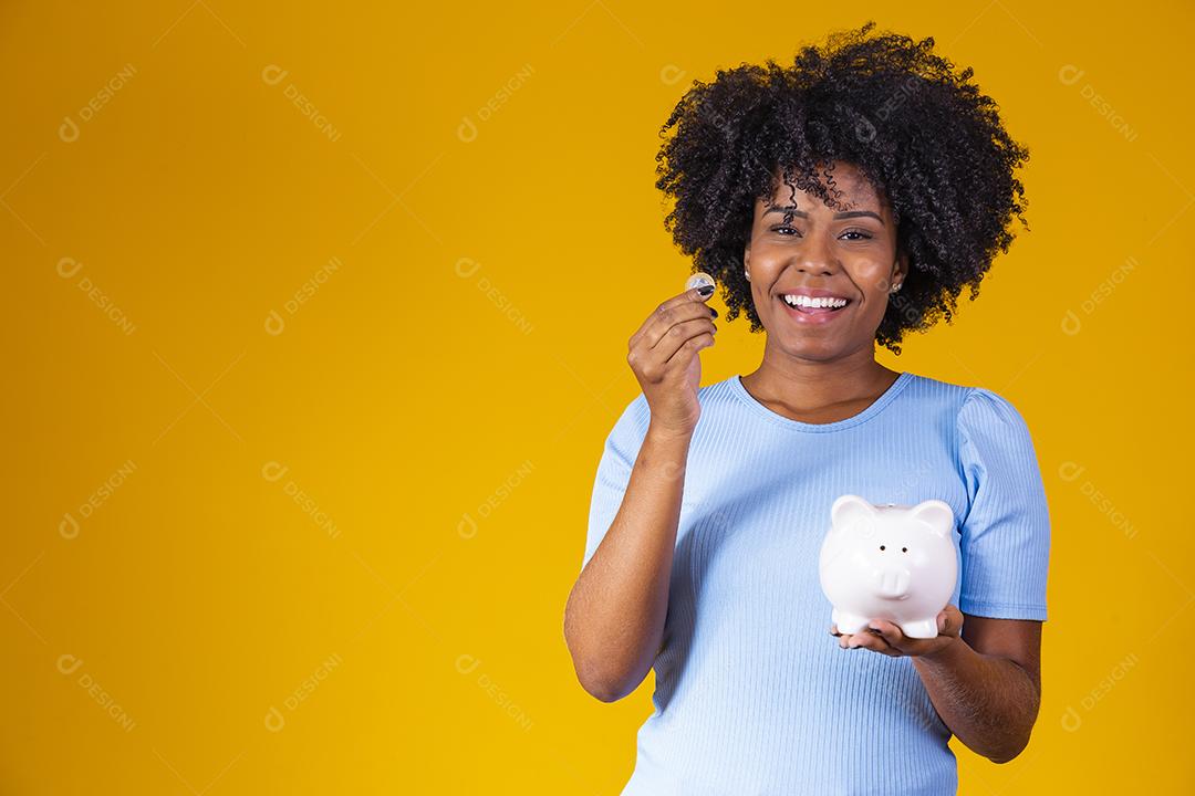 Mulher segurando moedas dinheiro cofre porco rosa fundo amarelo