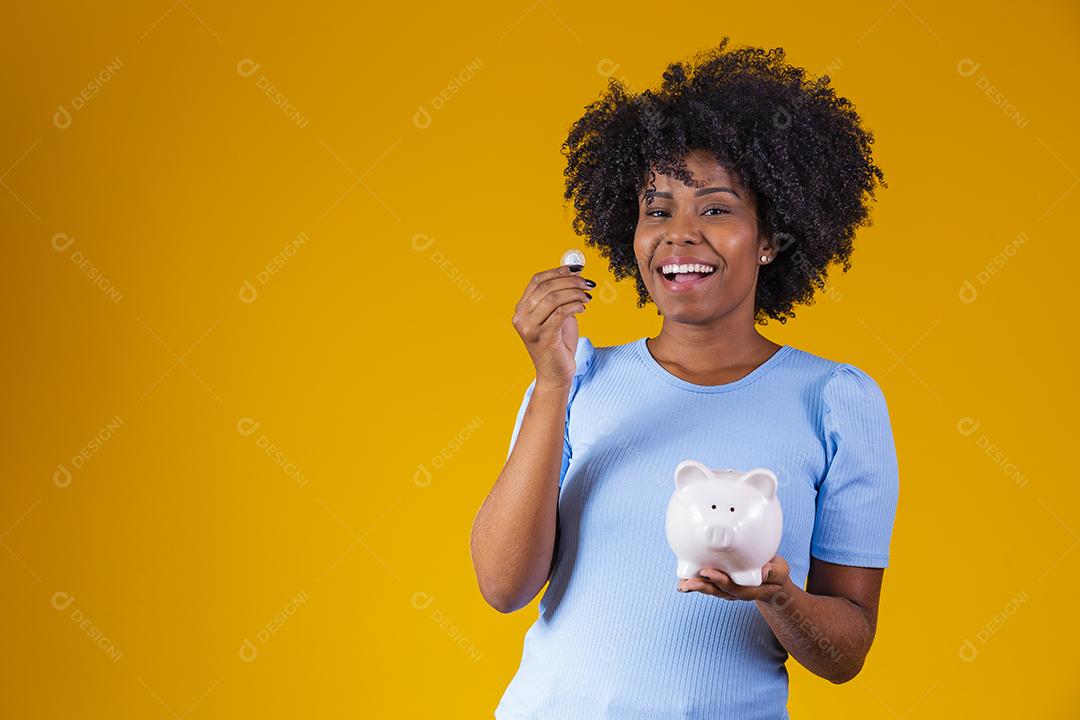 Mulher segurando moedas dinheiro cofre porco rosa fundo amarelo