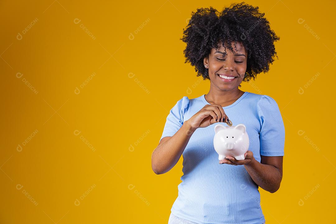 Mulher segurando moedas dinheiro cofre porco rosa fundo amarelo