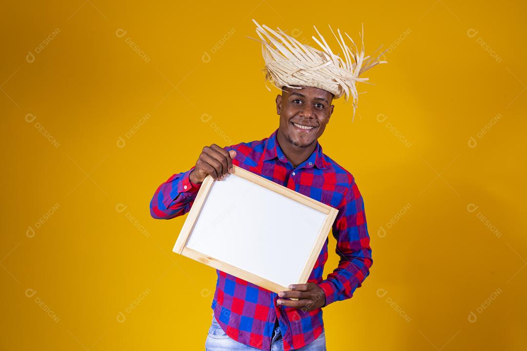 Homem afro brasileiro vestindo roupas típicas para a Festa Junina