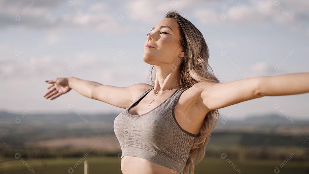 Linda mulher esticando os braços em um pico sobre o monte
