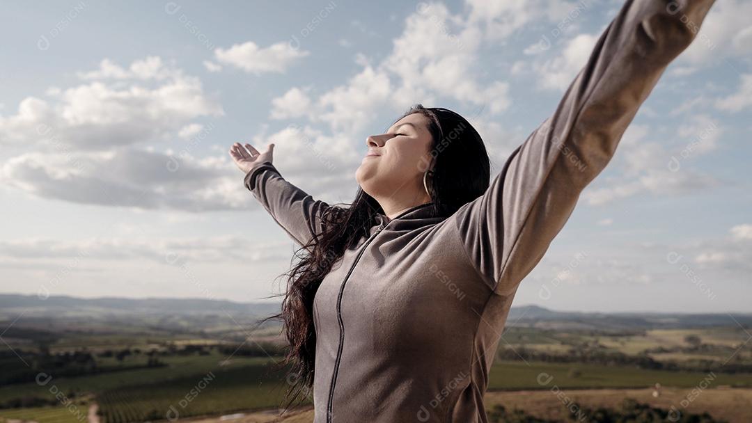 Linda mulher esticando os braços em um pico sobre o monte