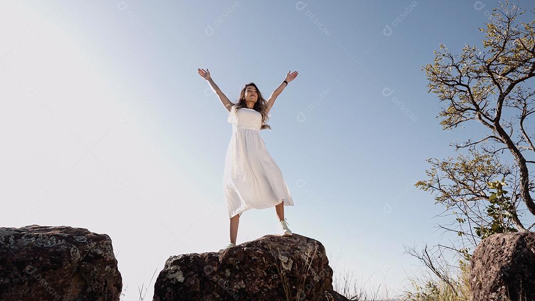 Linda mulher esticando os braços em um pico sobre o monte