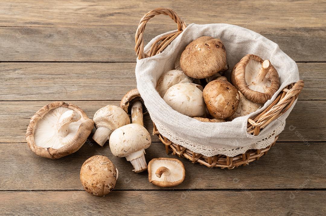 Cogumelos shimeji portobello e paris em uma cesta sobre a mesa de madeira