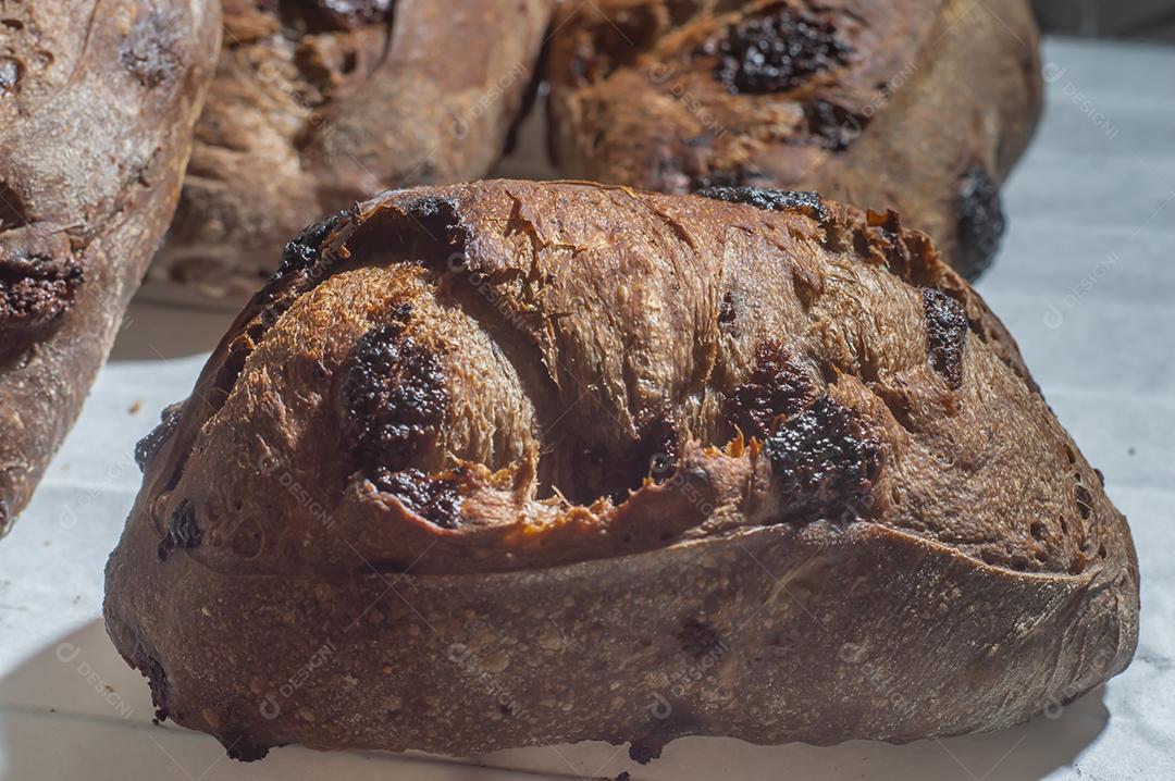 Pão francês de chocolate, pão de cacau assado com raspas de laranja e colocados juntos em uma prateleira.