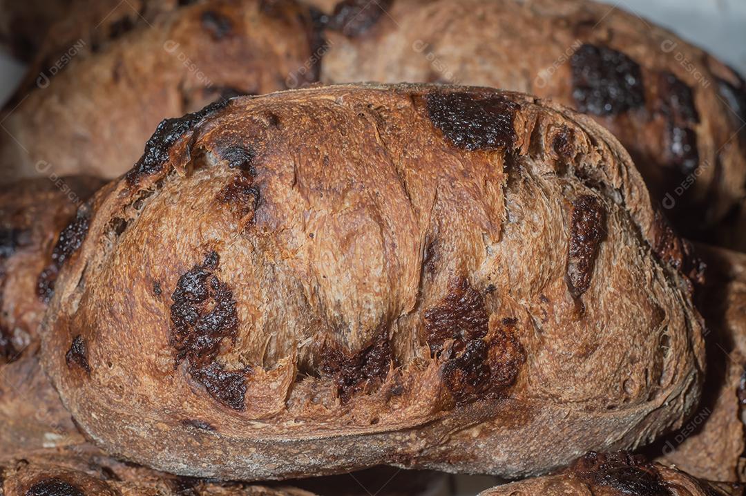 Pão francês de chocolate, pão de cacau assado com raspas de laranja e colocados juntos em uma prateleira.