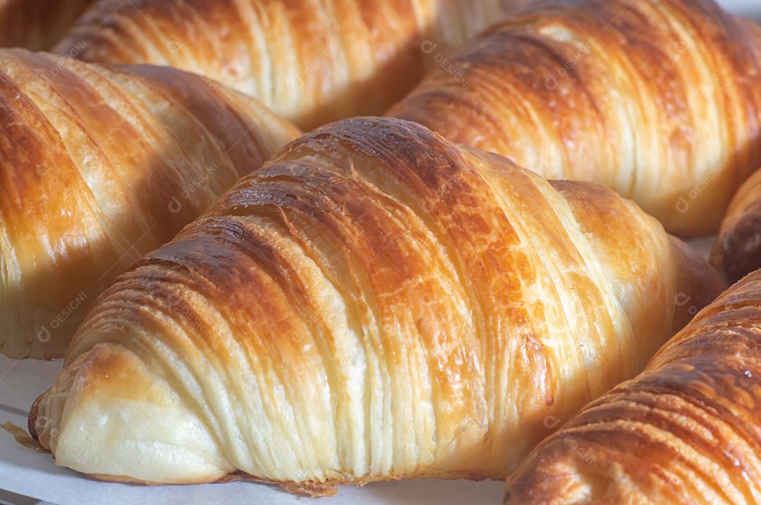 Deliciosos croissants caseiros em um papel manteiga branco, luz natural.