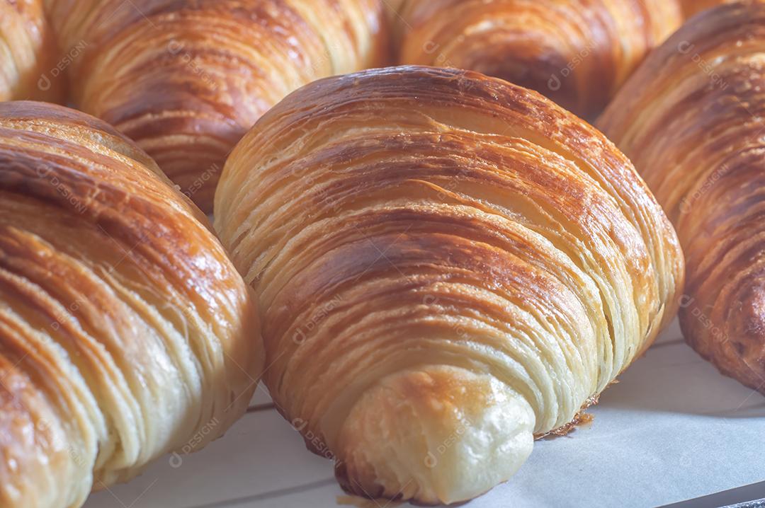 Deliciosos croissants caseiros em um papel manteiga branco, luz natural.