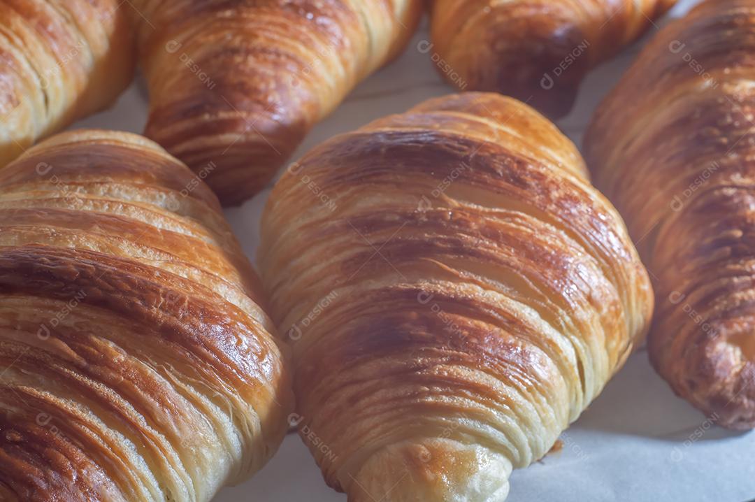 Deliciosos croissants caseiros em um papel manteiga branco, luz natural.